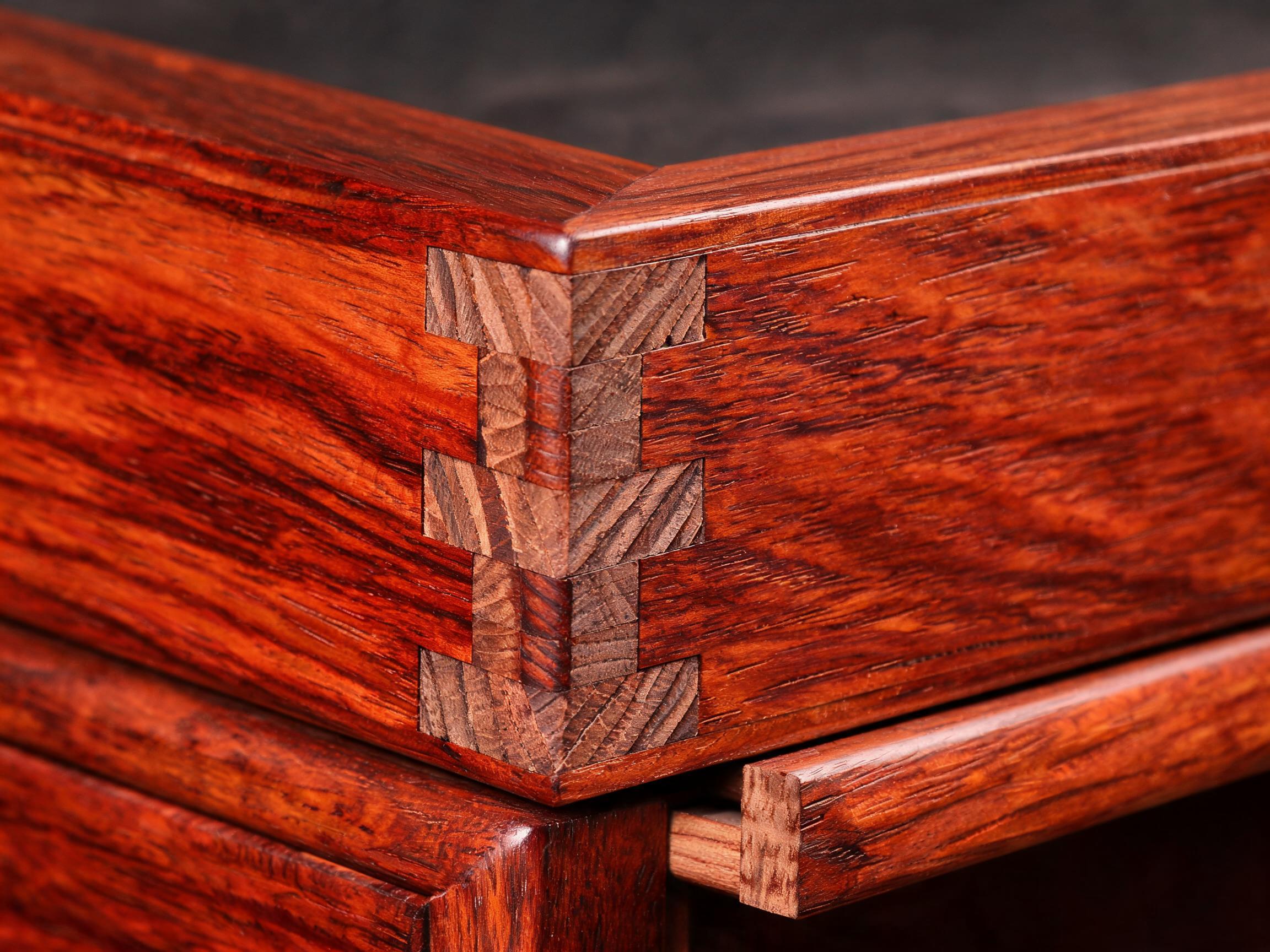 Hand-cut half-blind dovetail joint at a dresser drawer corner with the wooden runner visible beneath