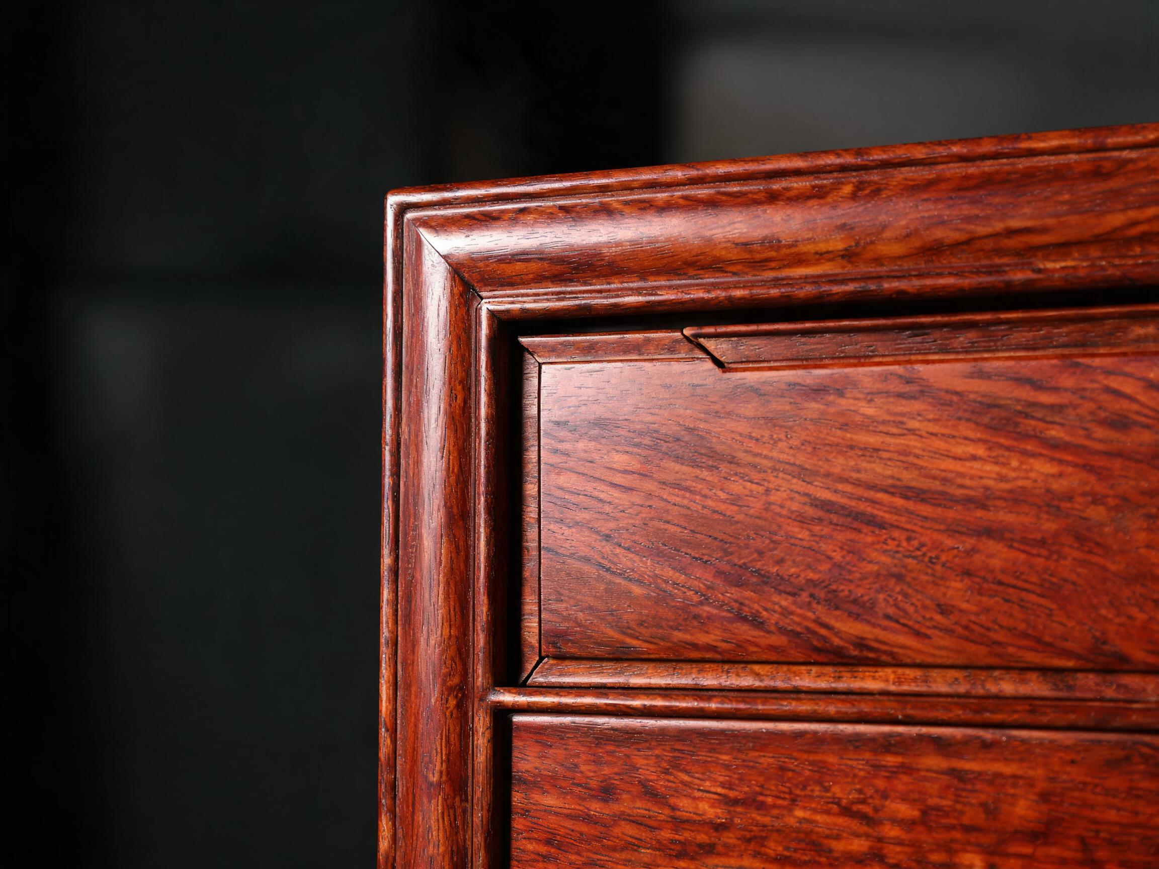 Close-up of a floating-panel wardrobe door showing the solid rosewood panel seated in a grooved mortise-and-tenon frame with its expansion gap