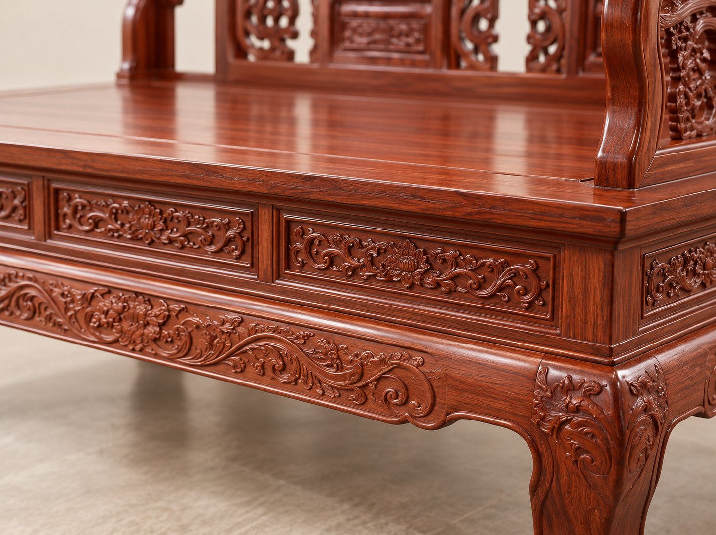 Close-up of the rosewood sofa seat edge and carved apron, showing the solid wood seat panel and continuous apron carving under the raw lacquer finish