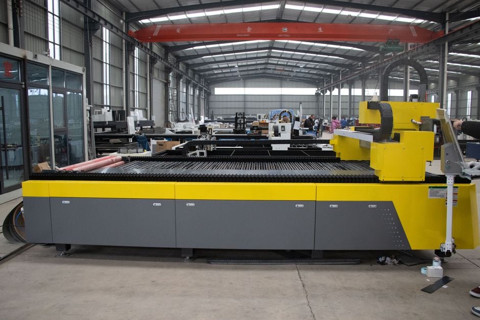 Yellow flatbed cutting machine in a factory workshop