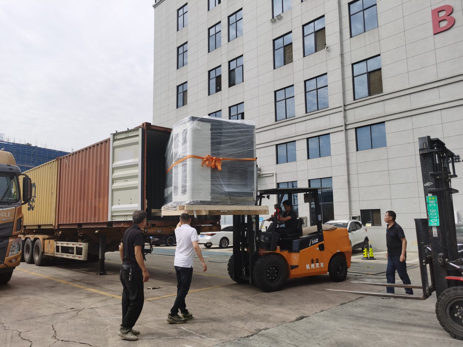 Wrapped machine being loaded into a container by forklift