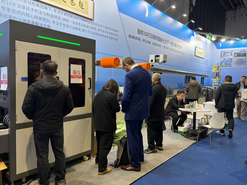 Automatic winding end of the Rongcai filament extrusion line at the Shanghai exhibition, with filament spools mounted and visitors talking with the Rongcai team
