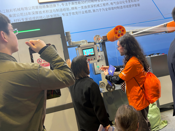 Visitors watching the Rongcai filament extrusion line run at the TCT exhibition in Shanghai, with an Rongcai engineer explaining the control screen